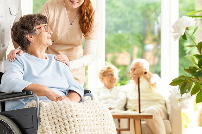 Seniorin sitzt im Rollstuhl und wird umsorgt