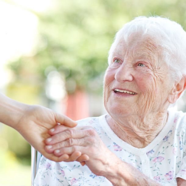 Seniorin lächelt und hält Hand vom Pflegeperson